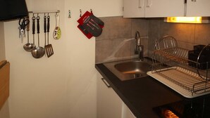 Een keuken met een spoelbak, een afwassysteem en verschillende keukengerei dat aan de muur hangt.