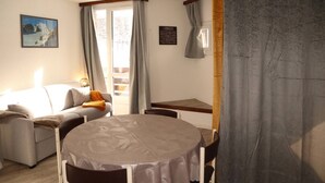 Een knusse woonkamer met een bank, een eettafel en uitzicht op het omliggende landschap door een raam.