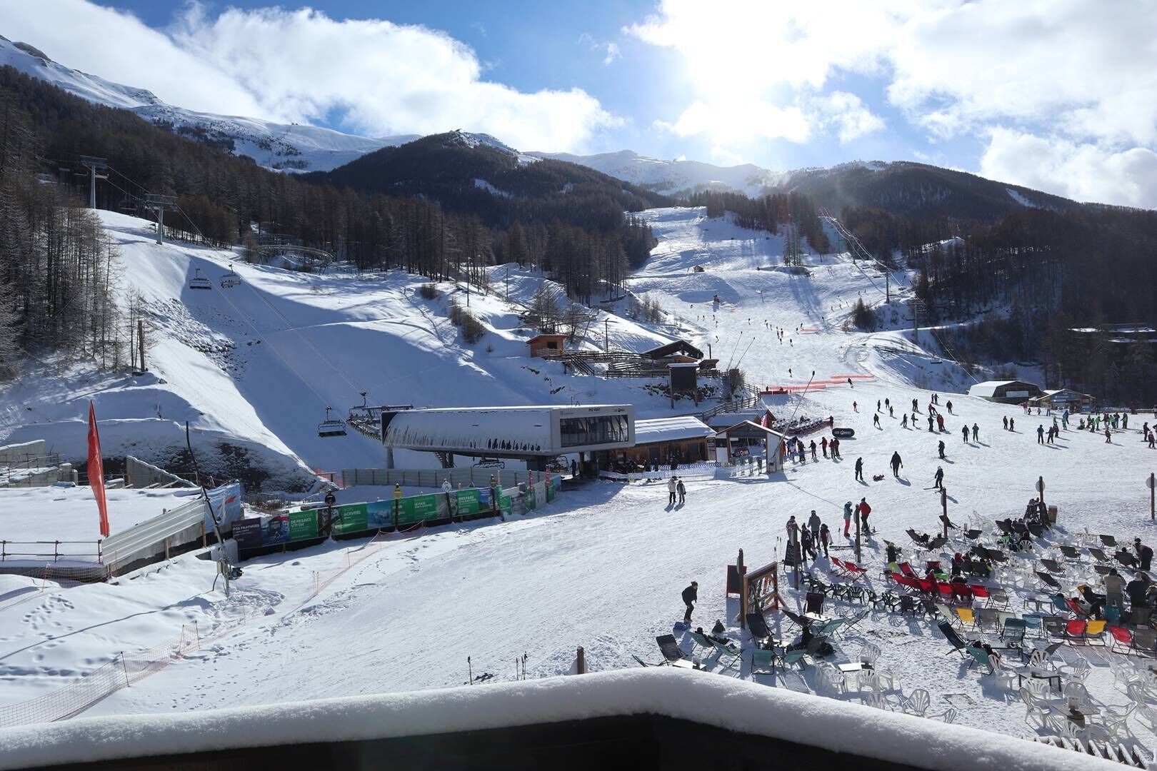 A ski resort with a chairlift, ski slopes, and a building with a sloped roof.