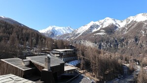 Eine Berghütte mit Holzbalkon und Blick auf schneebedeckte Berge.