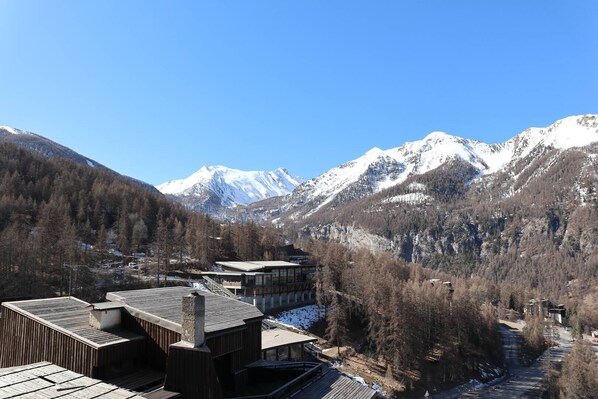 A mountain lodge with a wooden deck and a view of snow-capped mountains.