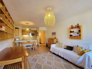 A cozy living room with a wooden table, a sofa, and a patterned rug. - Coeur de Station les Orres 1650 (LES ORRES 1650)