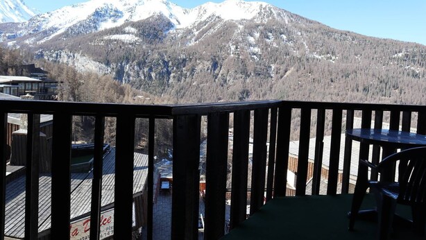 Eine Holzterrasse mit Blick auf schneebedeckte Berge.