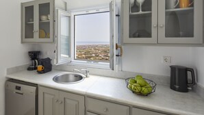 Een keuken met uitzicht op een stadsgezicht, een koffiezetapparaat, een waterkoker en een schaal fruit.