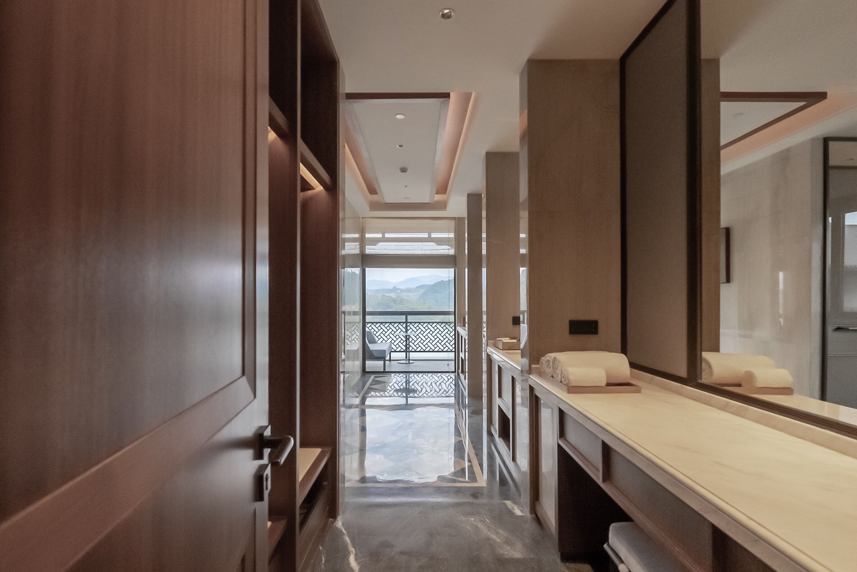 Un baño moderno con un espejo grande, armarios de madera y vistas a montañas.