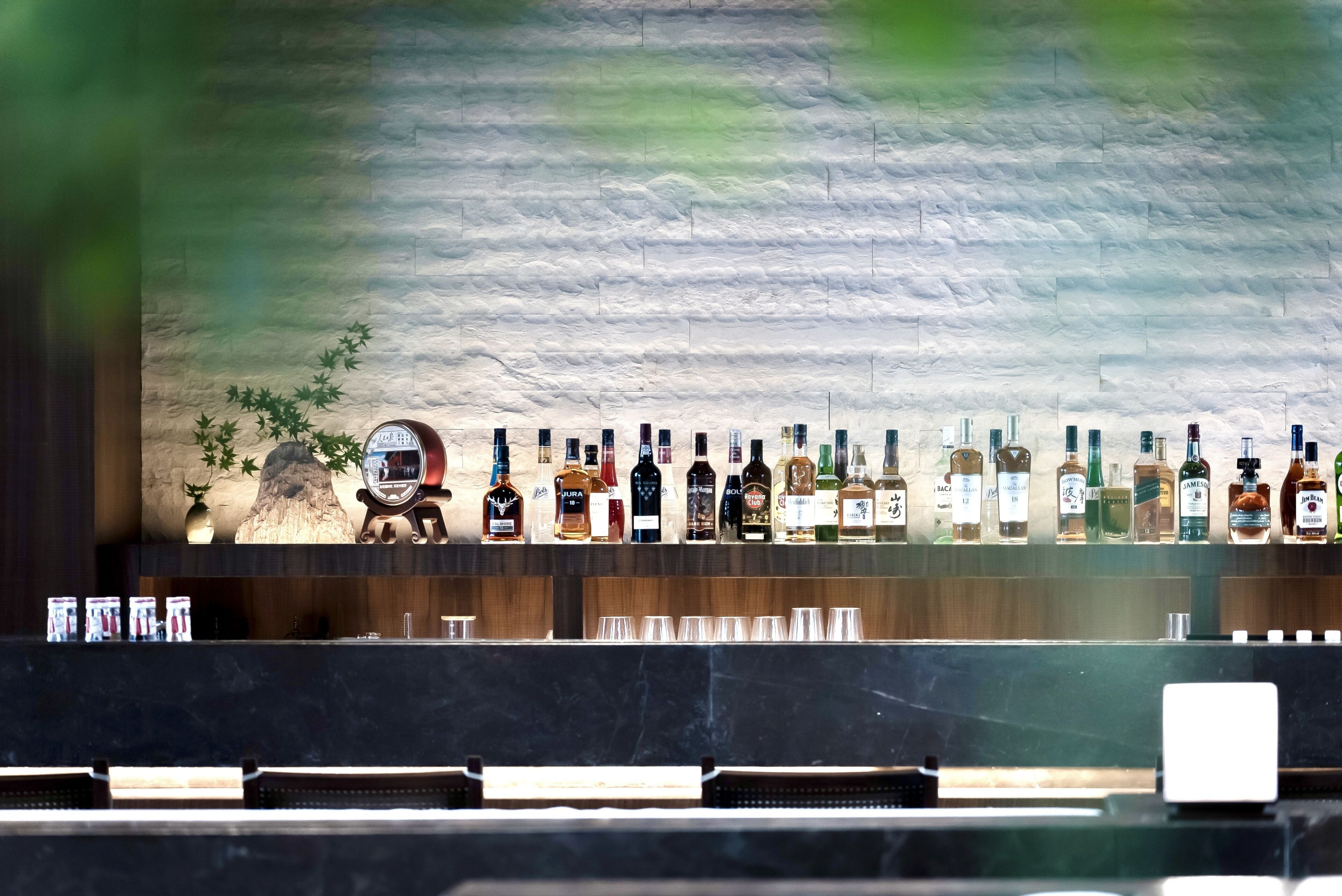 Um bar com uma variedade de garrafas de bebidas e copos à mostra.