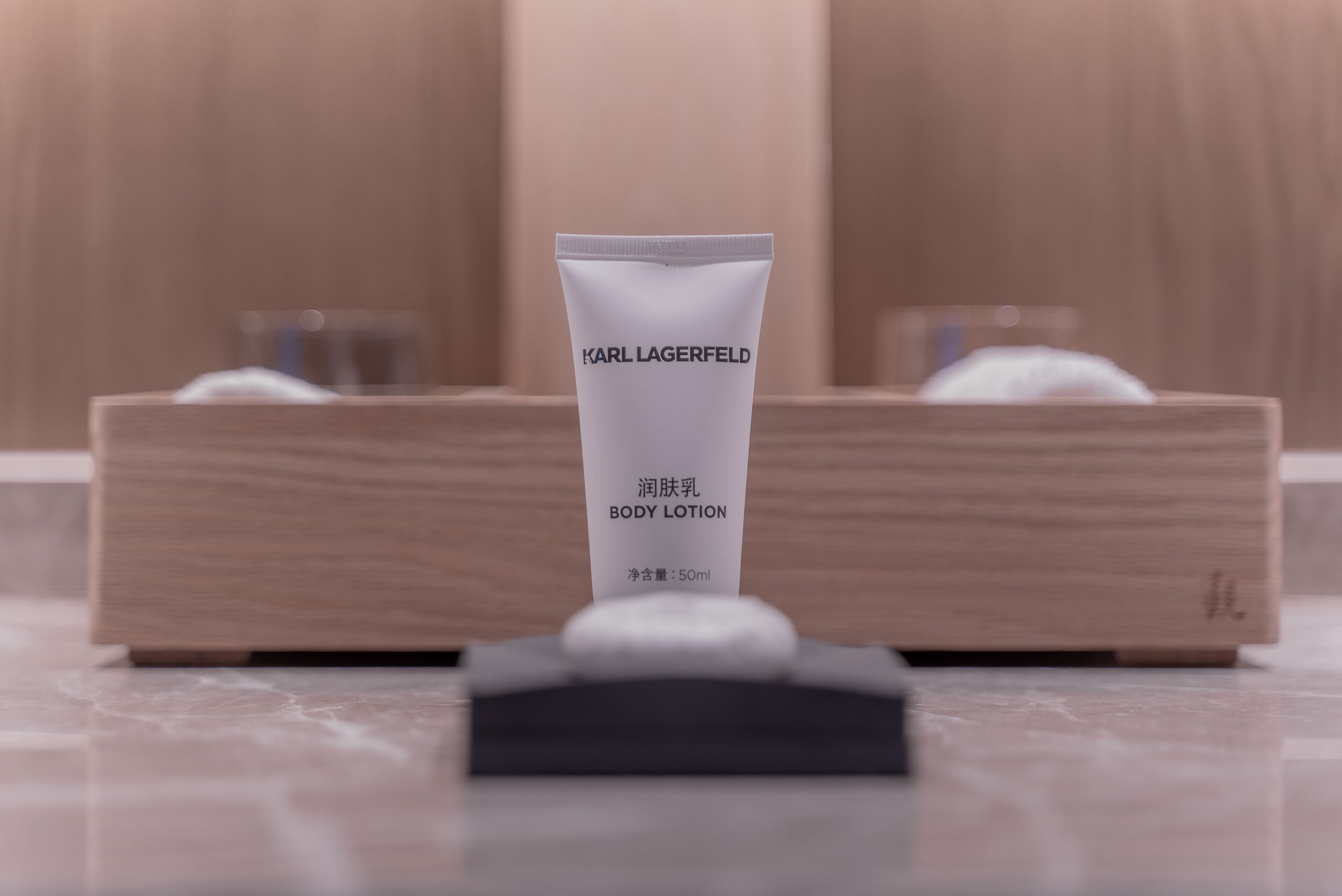 Un tubo de loción corporal con la etiqueta 'Karl Lagerfeld' sobre una superficie de madera.
