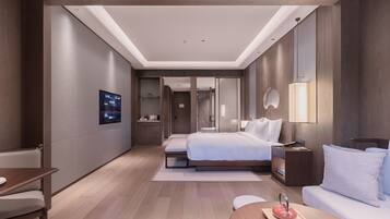 Una habitación de hotel moderna con una cama grande, mesitas de noche, un escritorio y un área de descanso.