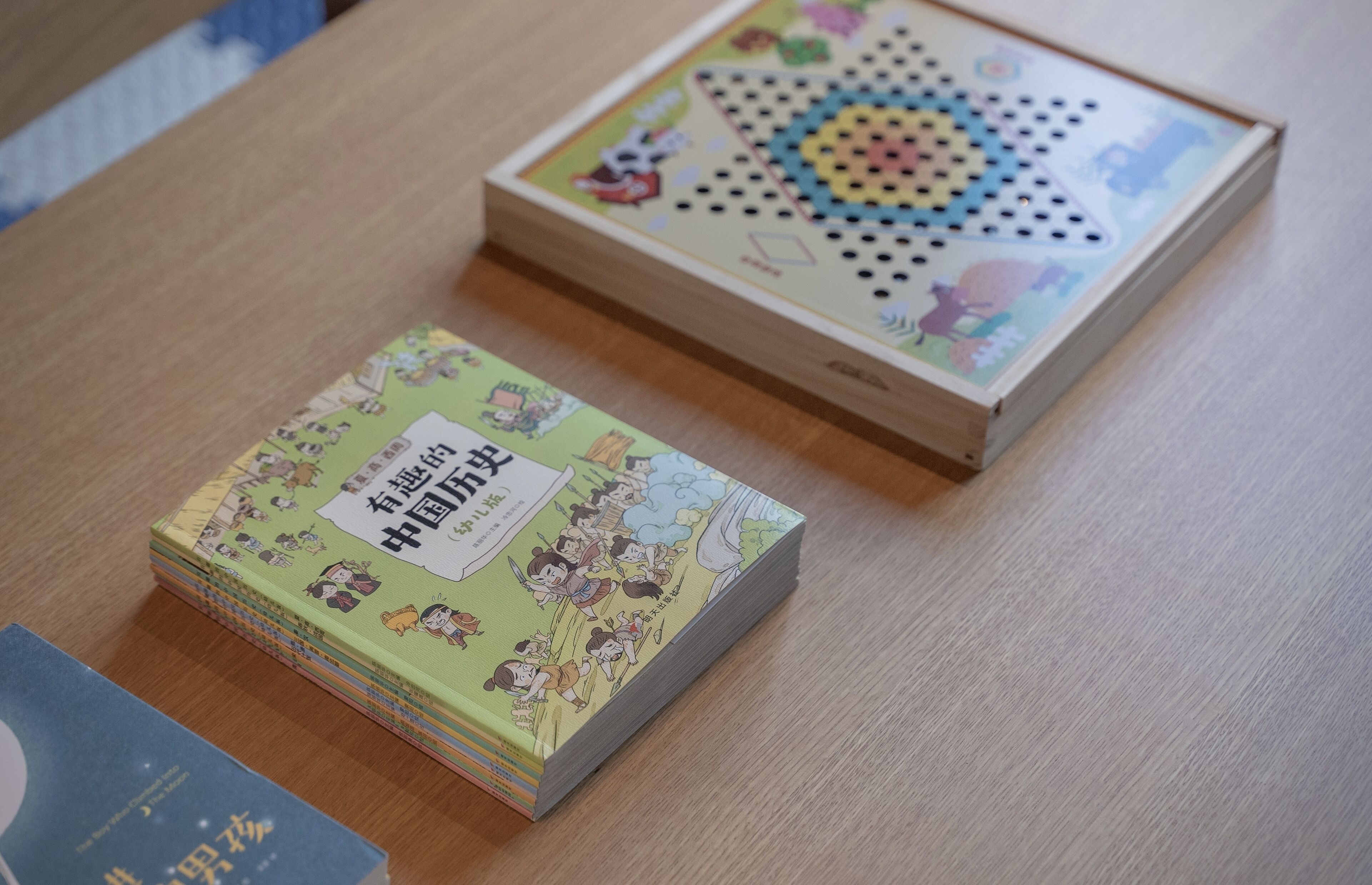 A wooden table with a stack of books and a puzzle box.