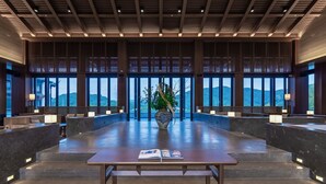 A spacious lobby with a central seating area, large windows offering a view of the mountains, and a decorative vase with plants. - Grand Dongshan (Shaoxing)