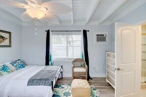 A bedroom with a bed, a chair, a dresser, and a ceiling fan.