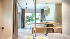 A modern bathroom with a large bathtub, a wooden vanity, and a large mirror. - Hotel BERGEBLICK  (Bad Toelz)
