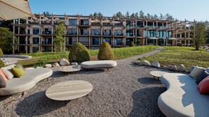 A modern building with multiple balconies and a landscaped outdoor area with seating and trees. - Hotel BERGEBLICK  (Bad Toelz)