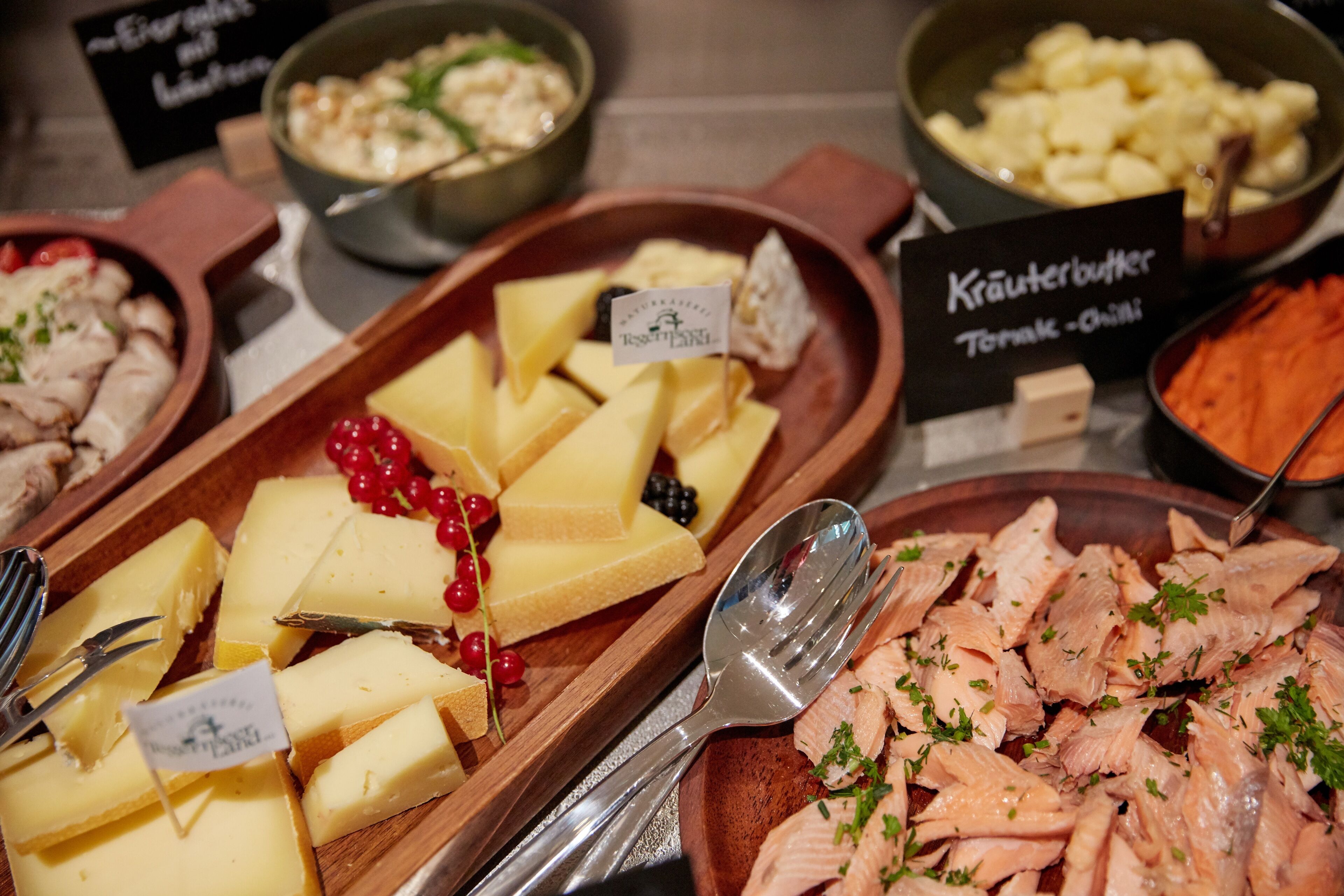 A variety of cheeses and meats on a buffet table, including labels for different types.