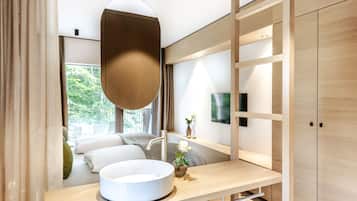 Une salle de bain moderne avec un lavabo rond, un miroir et une fenêtre donnant sur un paysage verdoyant.