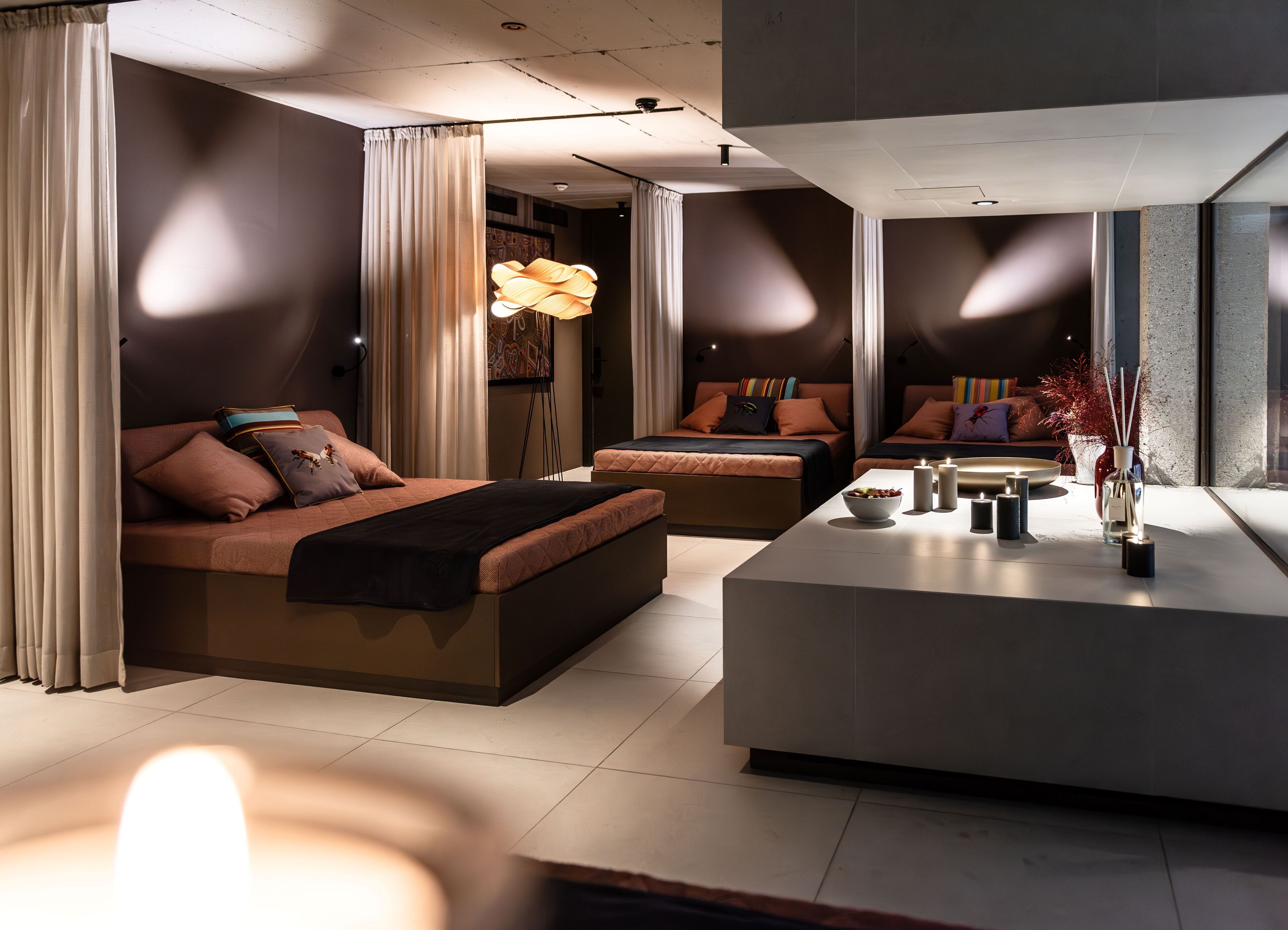 A modern bedroom with a large bed, a smaller bed, and a seating area with a table.