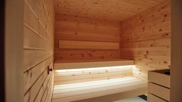 Interior de una cabaña de madera con banco, cajones y techo inclinado.