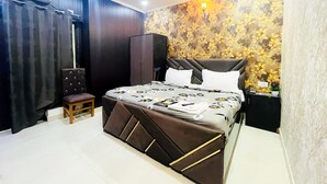 A bedroom with a bed, a wardrobe, a chair, and a nightstand. - Roomshala 005 Tom & Jerry (New Delhi)