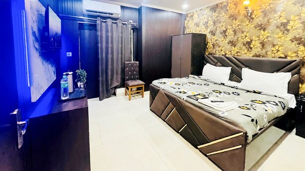 A modern bedroom with a bed, a ceiling fan, an air conditioning unit, a wardrobe, and a decorative wall. - Roomshala 005 Tom & Jerry (New Delhi)