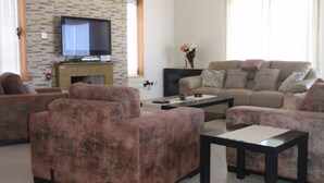 Sala de estar com televisão, sofá e mesa de centro.