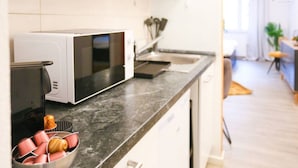 A modern kitchen with a microwave, sink, and a fruit basket.