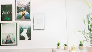A wall with framed pictures, a whiteboard with text, and small potted plants on a counter.