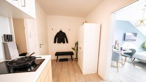 Een compacte keuken met een bankje, een koelkast, en een eethoek met tafel en stoelen.