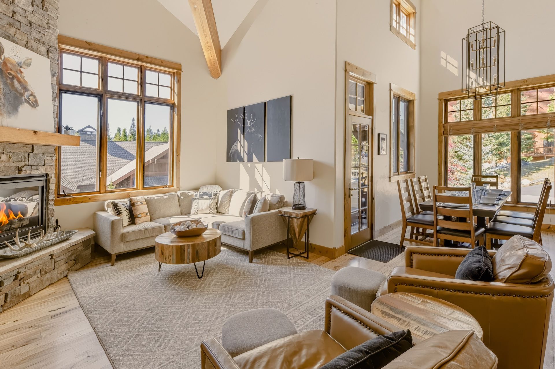 A spacious living room with a fireplace, a dining area, and large windows offering views of the outdoors.