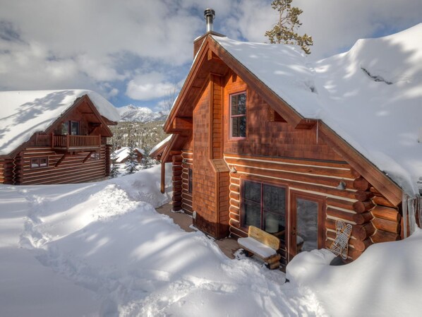 A log cabin with a wooden exterior, a chimney, and a bench outside.