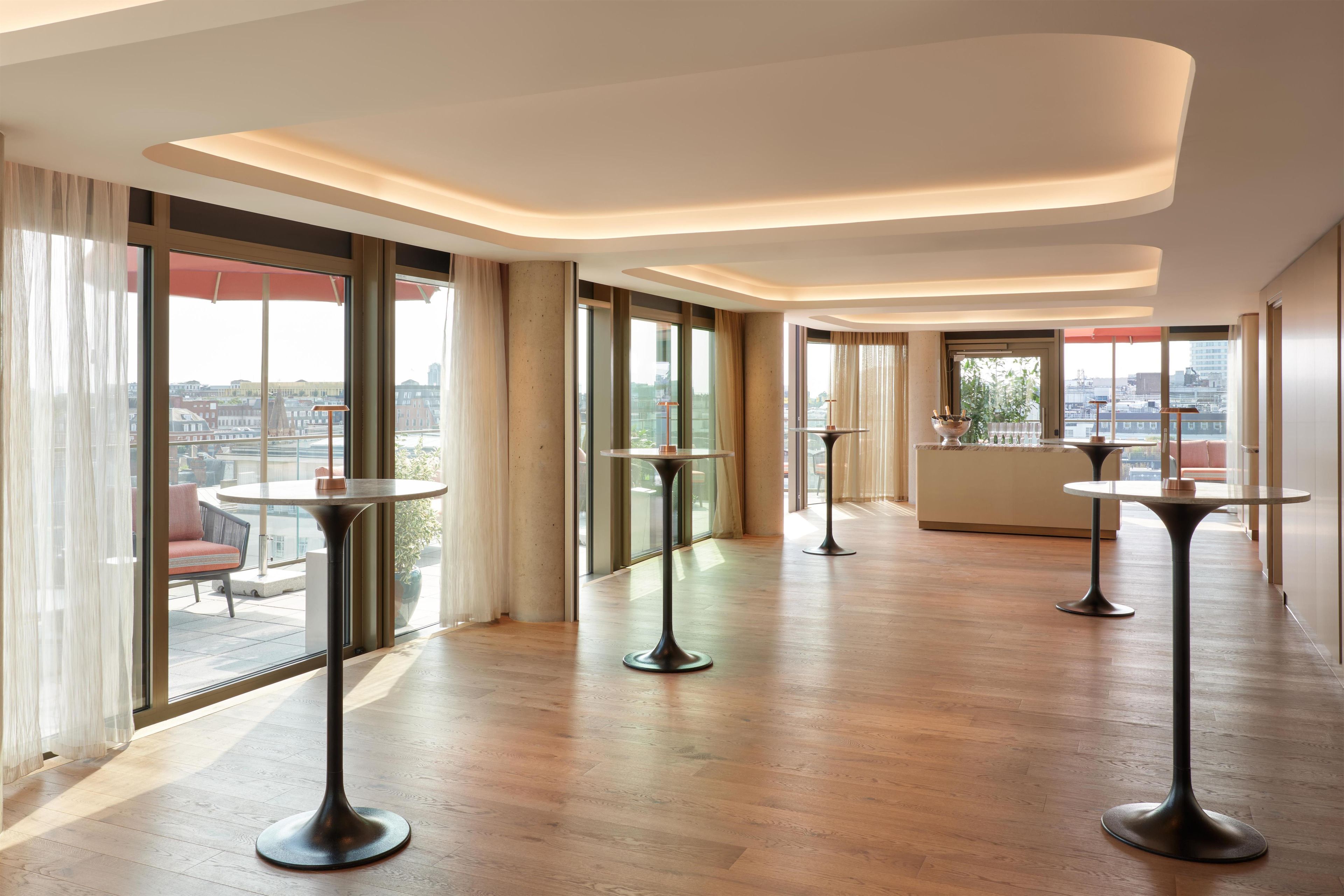 Un amplio vestíbulo de hotel con techos altos, ventanas grandes y vistas a la ciudad.