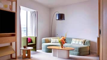Un salon avec un canapé vert, une table basse, un meuble pour la télévision et un lampadaire.