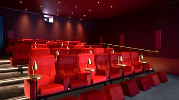 En biograf med rader av röda stolar, en liten filmduk längst fram och ett rött heltäckningsmatta på golvet.