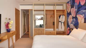 A hotel room with a bed, a wooden wardrobe, a desk, and a mirror.