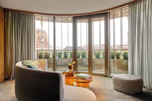 A corner room with a sofa, ottoman, and a small table with a book. - The BoTree London, Curio Collection by Hilton (London)