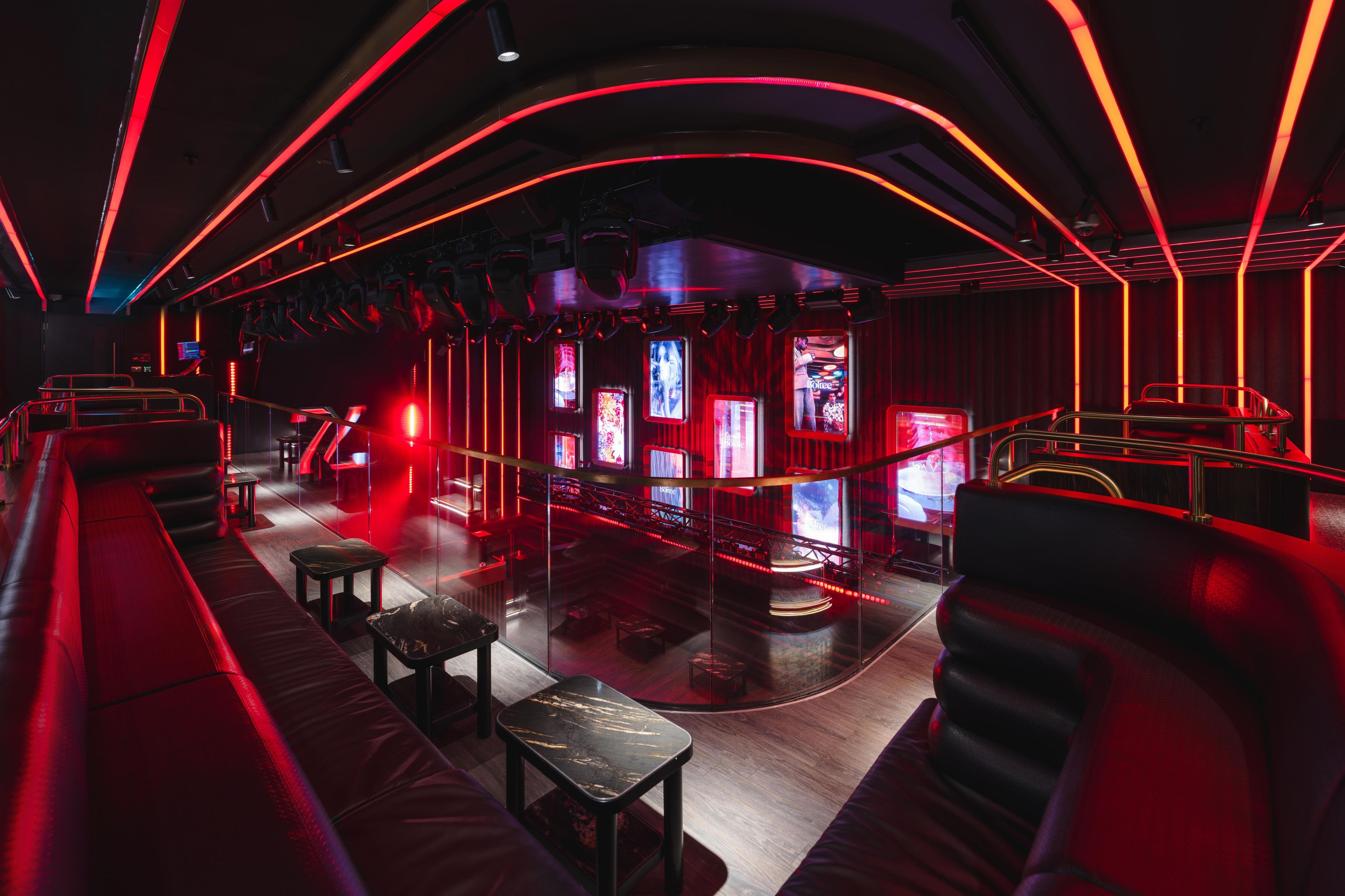 A modern interior with curved seating, a stage, and multiple screens.