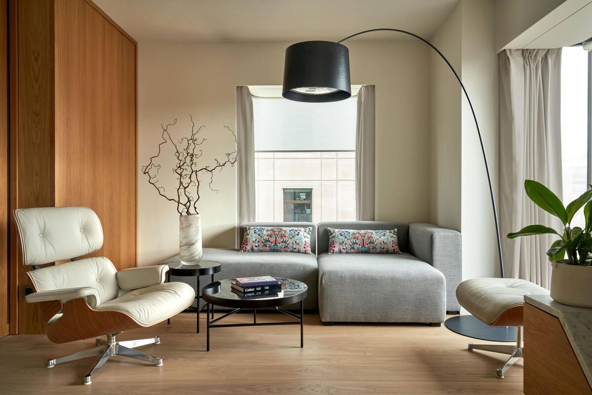 A modern living room with a sofa, armchairs, a coffee table, and a floor lamp.