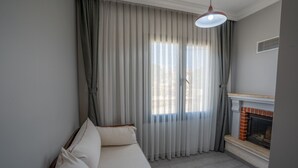Una sala de estar con sofá, chimenea y cortinas translúcidas.