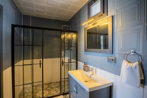 A modern bathroom with a glass-enclosed shower, a white sink, and a towel hanging on a metal rack. - Adaline Cunda Otel (Ayvalik)