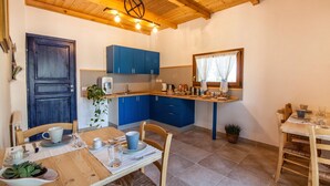 Een kleine keuken met blauwe kastjes, een houten aanrecht en een eethoek met een tafel gedekt voor twee personen.