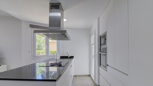A modern kitchen with white cabinets, a black countertop, and stainless steel appliances. - Playamar by Rentallorca (Puerto de Alcudia)