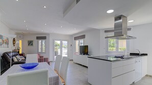 A modern kitchen with a central island, white cabinetry, and a built-in stove. - Playamar by Rentallorca (Puerto de Alcudia)