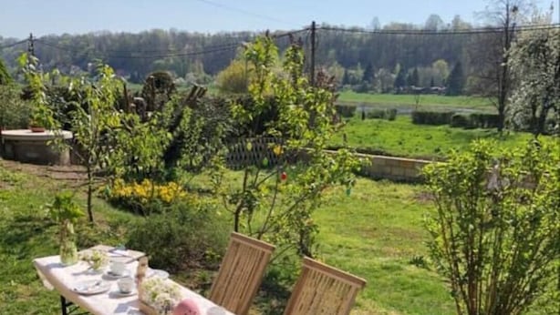 Un'area pranzo all'aperto con un tavolo apparecchiato per quattro persone, circondato da sedie di legno.