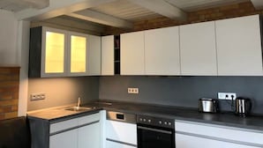 Una cucina moderna con mobili bianchi, forno integrato e macchina da caffè sul piano di lavoro.
