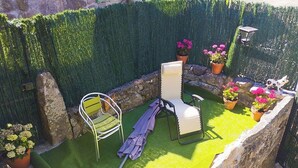 A small outdoor seating area with two chairs, a table, and a potted plant. - A beira da cortella (Melón)