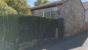 A stone building with a tiled roof, a window with white frames, and a stone wall. - A beira da cortella (Melón)