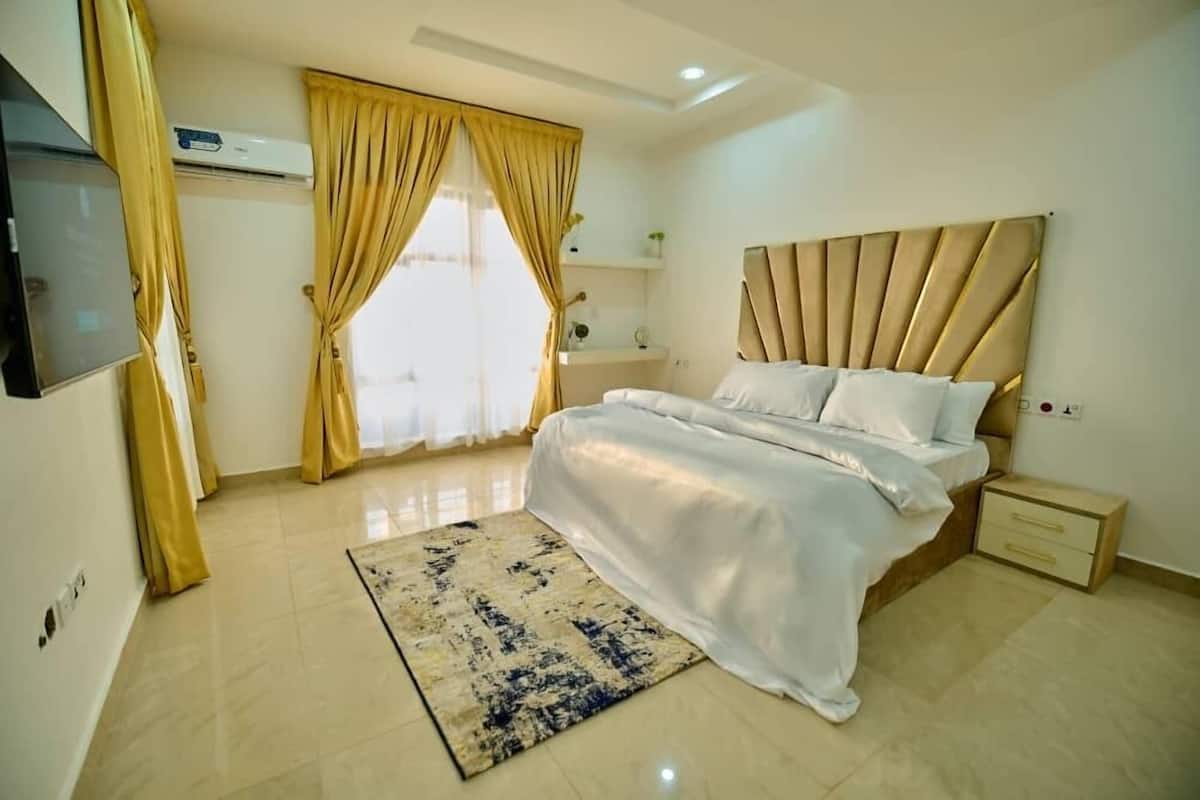 A modern bedroom with a large bed, a bedside table, and a TV mounted on the wall.