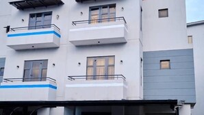 Um edifício moderno de vários andares, com dois carros estacionados na frente.