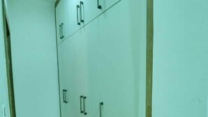 Um corredor com um guarda-roupa grande, com várias portas e gavetas.