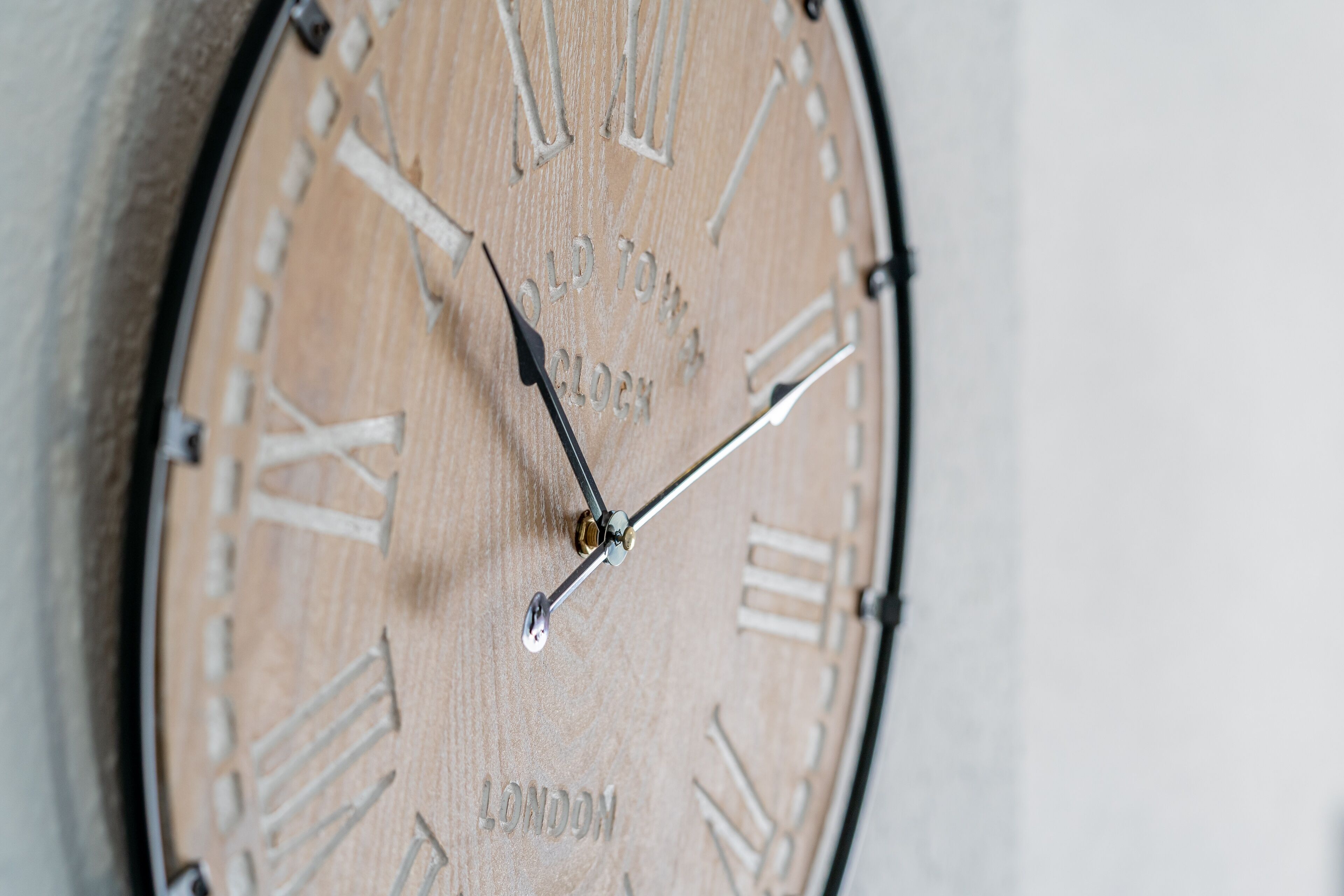 A close-up of a wooden wall clock with Roman numerals and the word "LONDON" engraved on it.