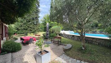 Un espace patio avec une piscine, des sièges d’extérieur et une statue.